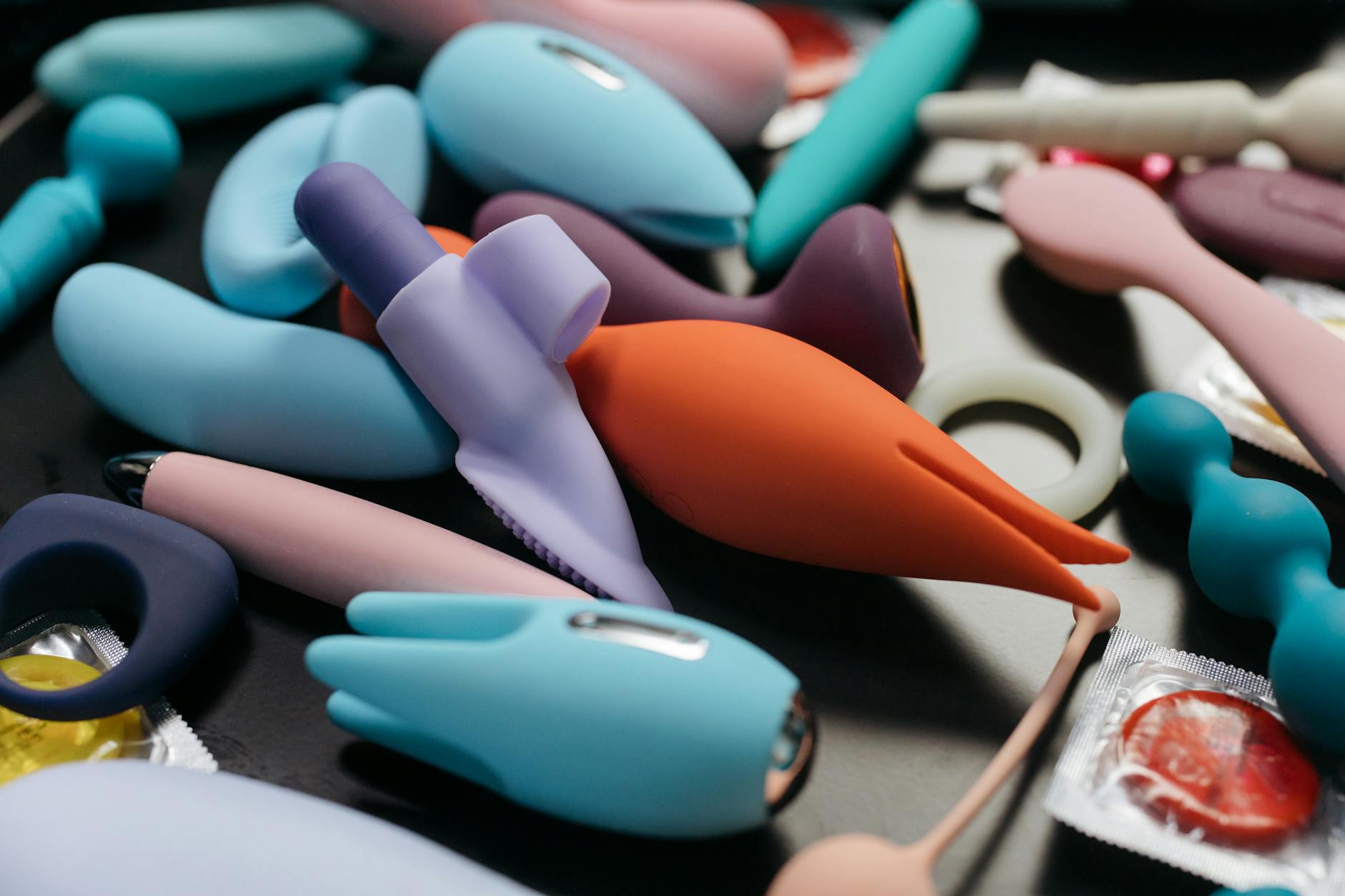 Woman thoughtfully holding blue and pink silicone vibrators while exploring sensation recovery options